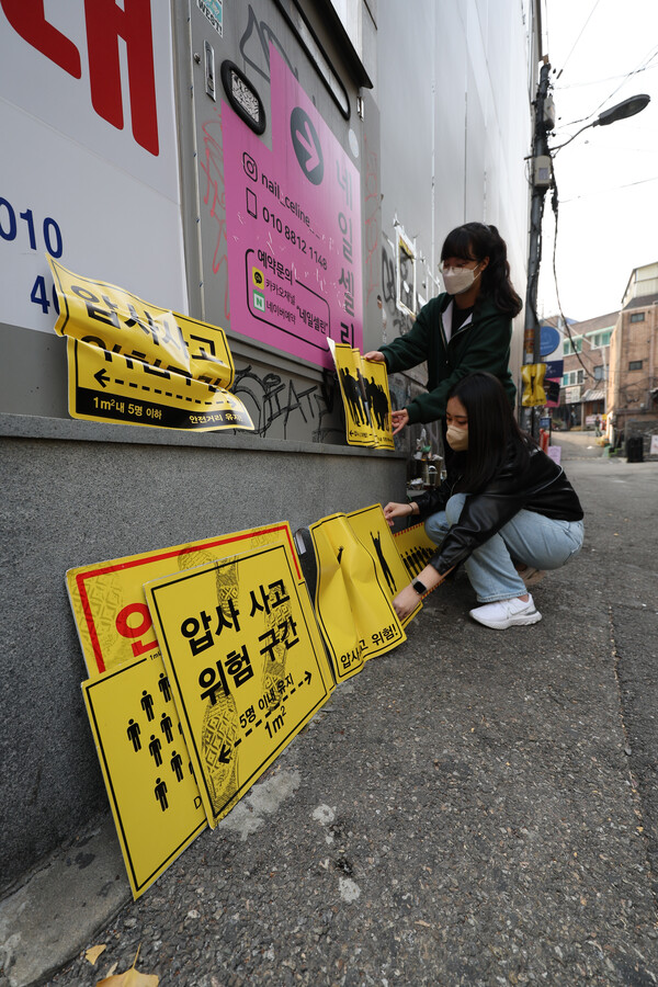 10일 오전 서울 마포구의 한 골목에 군중 안전을 위한 표지판 도입을 촉구하며 이제석 광고연구소 관계자들이 설치한 안전 표지판 뒤로 시민들이 이동하고 있다.이제석 광고연구소는 이번 이태원 참사를 계기로 인파가 몰리는 협소 지역을 대상으로 군중 안전 관련 표지판의 개발과 도입을 각 지자체, 국토교통부 등에 공문을 통해 요구할 계획이라 밝혔다. 2022.11.10 연합뉴스