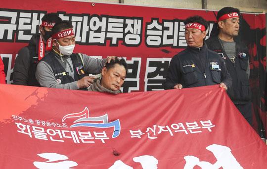 화물연대본부 총파업 엿새째인 29일 오후 부산 강서구 부산신항 삼거리에서 부산본부 조합원들이 정부의 업무개시명령에 반발하는 집회를 열고 부산지역본부 송천석 본부장이 삭발하고 있다. 연합뉴스 