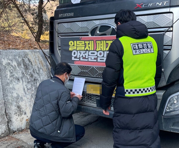 2일 오전 강원 영월군 한반도면 한일현대시멘트 앞에서 국토교통부와 영월군청 관계자들이 경찰 엄호 속에 민주노총 공공운수노조 화물연대본부(화물연대) 노조원 차량에 업무개시명령서를 붙이고 있다. 2022.12.2 [강원경찰청 제공] 연합뉴스