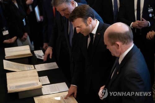 미국을 방문한 에마뉘엘 마크롱 프랑스 대통령(가운데)이 지난 30일 워싱턴의 의회도서관에서 기후변화와 생물다양성을 주제로 한 미국 상원의원들과의 업무오찬에 앞서 상원의원들과 함께 관련서류를 보고 있다. 업무오찬에서 마크롱 대통령은 IRA와 관련한 유럽의 불만을 집중 제기했다.  2022.11.30  AFP연합뉴스 