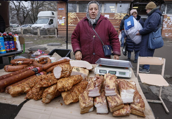 도네츠크 공화국의 마리우폴 외곽의 한 시장에서 지난 10일 주민들이 빵을 팔고 있는 야외 매대 부근에 모여 있다.  전쟁 전 인구가 55만명이었던 마리우폴에는 현재 30만명 정도가 남아 있지만 5000여명이 사망하고 주택의 70%가 파괴됐다. 우크라이나 영토였던 마리우폴은 러시아군과 도네츠크 공화국군이 3달에 걸친 포위공격 끝에 지난 5월 말부터 점령하고 있다.  2022. 12.11 EPA연합뉴스