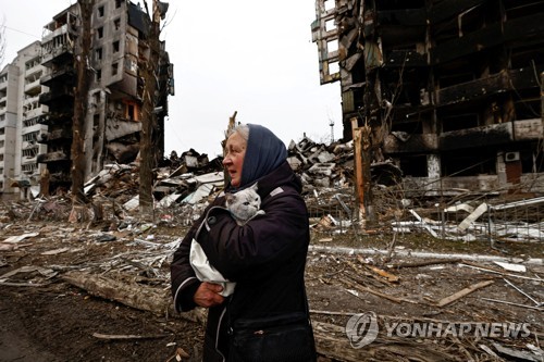 러시아의 폭격으로 파괴된 건물 앞 지나는 우크라이나 여성[로이터 연합뉴스 자료사진.