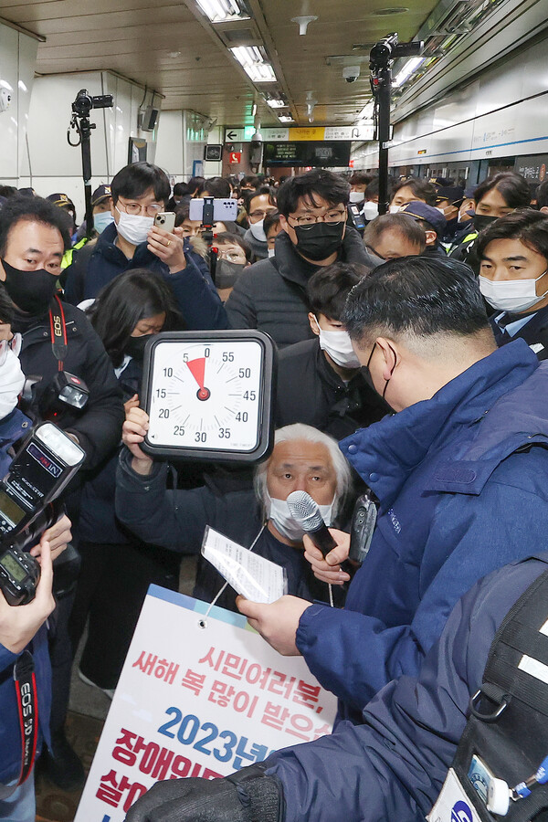 박경석 전국장애인차별철폐연대(전장연) 대표가 2일 오전 서울 지하철 4호선 삼각지역 승강장에서 5분이 표시된 시계를 들고 지하철 탑승을 시도하고 있다. 서울중앙지법은 지난달 19일 서울교통공사가 전장연과 이 단체 박경석 대표 등을 상대로 낸 손해배상 소송을 강제조정하며 전장연이 지하철 승하차 시위로 5분을 초과해 지하철 운행을 지연시키면 1회당 500만원을 공사에 지급하도록 했다. 2023.1.2. 연합뉴스