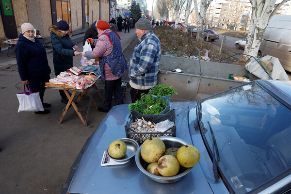 4일(현지시각) 우크라이나 동부 도네츠크주 바흐무트의 한 거리에서 상인들이 가판대와 자동차 위에 식품 등을 진열해 팔고 있다. 이 임시 노점은 정교회 성탄절(매년 1월 7일)을 앞두고 열린 것이다. 2023.01.05 로이터 연합뉴스
