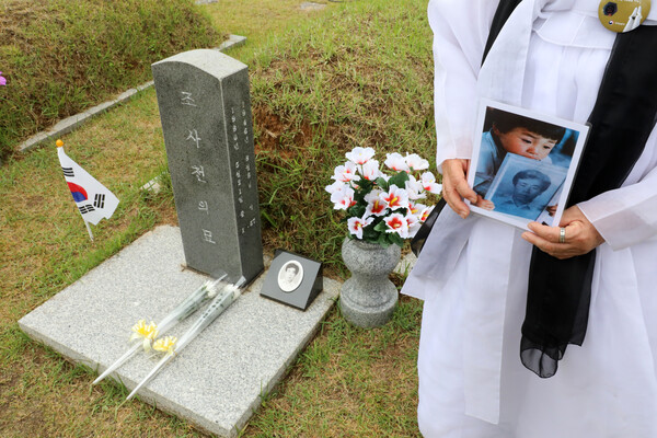 2019년 5월 18일 오전 광주 국립5·18민주묘지 희생자 조사천의 묘역에서 유가족이 관련 사진을 들고 서 있다. 유가족이 들고 있는 사진은 조사천씨의 영장을 그의 아들이 들고 있는 모습으로, 5·18의 참상을 알린 사진으로 유명하다. 2019.5.18. 연합뉴스