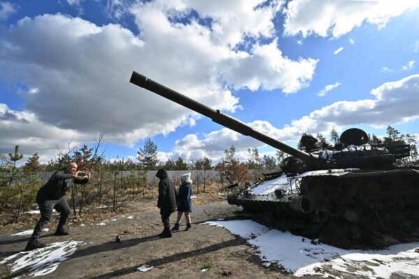 전쟁이 일상이 된 우크라이나. 한 남자가 6일 러시아군의 부숴진 탱크 앞에서 아이들 사진을 찍고 있다. 2023.3.6 AFP 연합뉴스 