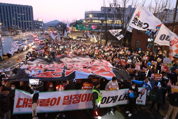 18일 '6차 전국집중촛불(31차 촛불대행진)'에 참가한 시민들이 서울 종로구 일본 대사관 앞에서 윤석열 대통령이 합성된 대형 욱일기를 찢는 행사를 하고 있다. 2023.3.18. 촛불행동 제공