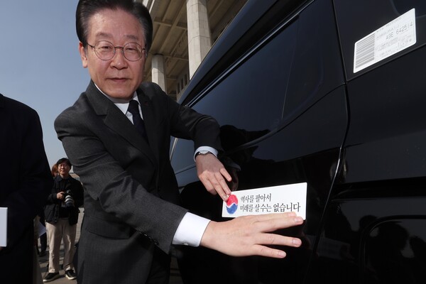 더불어민주당 이재명 대표가 22일 오전 서울 여의도 국회 본청 앞에서 열린 대일굴종외교 규탄 태극기달기 운동 행사에서 '역사를 팔아서 미래를 살 수는 없습니다' 문구가 담긴 태극기 스티커를 차량에 부착하고 있다. 2023. 3. 22. [공동취재] 연합뉴스