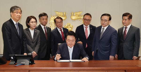 윤석열 대통령이 지난해 5월 10일 서울 용산에 새로 마련된 대통령 집무실에서 1호 법안에 서명하고 있다.뒷줄 왼쪽부터 김대기 비서실장, 강인선 대변인, 최상목 경제수석, 최영범 홍보수석, 안상훈 사회수석, 김성한 국가안보실장, 김용현 대통령경호처장. 2022.5.10. 연합뉴스