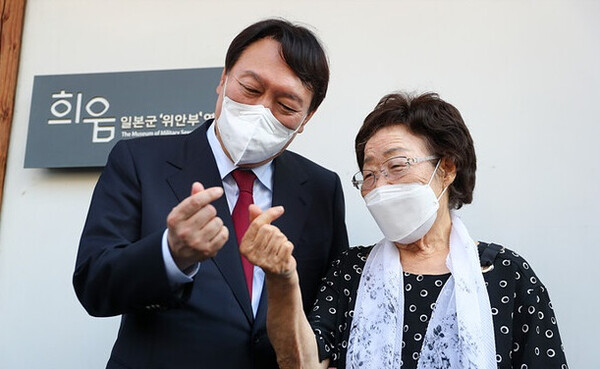 지난 2021년 9월 11일, 대선 후보 당시의 윤석열 대통령이 이용수 할머니와 함께 카메라 앞에서 손가락 하트를 만들어 보이고 있다.  윤석열 대선캠프에서 배포한 사진이다.