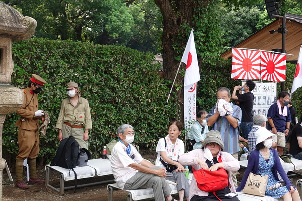 일본 패전일이자 한국 광복절인 15일 오전 도쿄 지요다구의 야스쿠니신사 경내에 전범기인 욱일기가 내걸려 있다. 그 옆으로는 2차 세계대전 당시 일본군 복장의 우익 인사들이 서 있다. 2022.8.15 연합뉴스