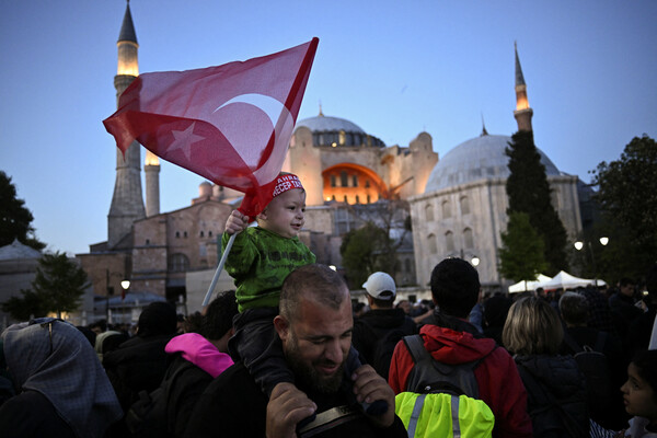  튀르키예 대선 1차투표를 하루 앞둔 지난 13일 이스탄불의 하기아 소피아 모스크 앞에 주민들이 몰려 있다. 아빠의 등에 업힌 아기가 튀르키예 국기를 들고 있다. 2023.5.13. 로이터 연합뉴스 