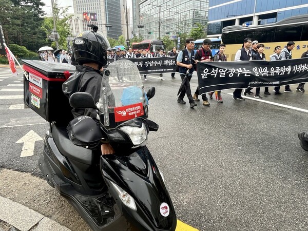 21일 오전 서울 종로구 정동사거리에서 배달플랫폼 노조원이 고 양회동 열사 운구차를 따라 장례행렬 중인 건설노조원들을 격려하고 있다. 건설노조원들도 목례로 답했다. 2023.6.21 김성진 기자