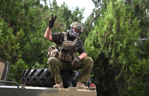 바그너 그룹 전투원이 24일 러시아 남부도시 로스토프 온돈의 남부군구 사령부 근처 거리에서 손가락으로 승리의 V자 모양을 그려 보이고 있다. 2023.06.24. 로이터 연합뉴스 