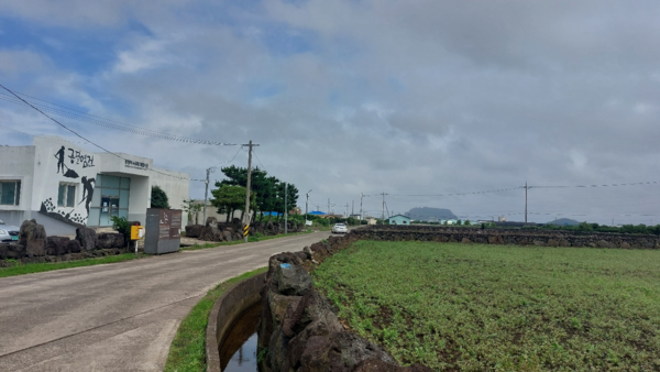 종달리 모래소금 체험시설 밖으로 원래 모래염전이던 들판이 펼쳐진다. 멀리 성산일출봉이 보인다. © 이봉수 