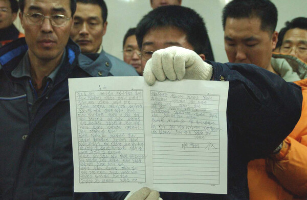 2002년 1월 9일 경남 창원시 귀곡동 두산중공업에서 분신자살한 배달호씨의 유서를 경찰이 노조와 유가족이 참가한 가운데 공개하고 있다. 2002.1.9. 연합뉴스 자료사진