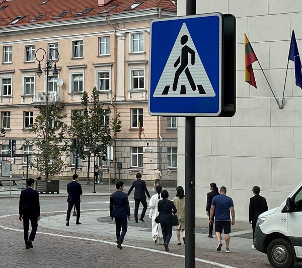 리투아니아 수도 빌뉴스의 올드타운 거리를 대낮에 경호원들을 대동하고 활보하는 걸어가는 대통령 부인 김건희 여사. 리투아니아 언론매체 '주모네스'가 12일 보도했다. 2023 07 12. [주모네스 홈페이지 캡처]