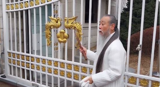 윤석열·김건희 대통령 부부의 멘토로 알려진 천공이 지난달 22일 청와대 문에 있는 노란색 봉황장식을 가리키며 일행에 그 유래를 설명하고 있다. 2023.1.22. 독자 제공