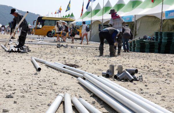 전북 부안군의 새만금 세계 스카우트 잼버리 행사장에서 행사 관계자들이 각국 대표단의 문화 홍보 부스 앞에 설치된 그늘막을 해체하고 있다. 2023.8.7. 연합뉴스 