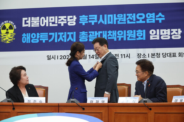 더불어민주당 이재명 대표가 14일 오전 국회에서 열린 후쿠시마원전오염수 해양투기저지 총괄대책위원회 임명장 수여식에서 유정주 의원으로부터 '후쿠시마 원전 오염수 NO!'라는 문구가 새겨진 홍보 배지를 전달받고 있다. 2023.8.14. 연합뉴스