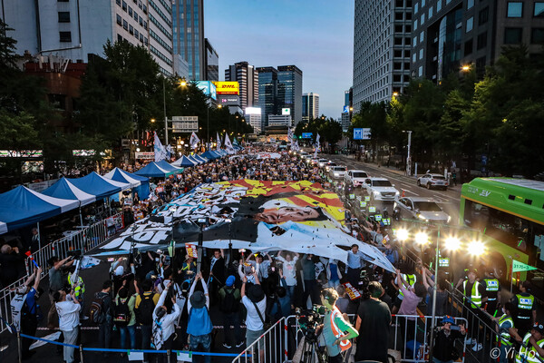 3일 오후 서울 지하철 시청역 앞 대로에서 열린 '42차 촛불대행진'에서 윤석열 대통령과 욱일기가 합성된 대형 현수막을 찢는 모습. 2023.6.3. 사진 이호 작가