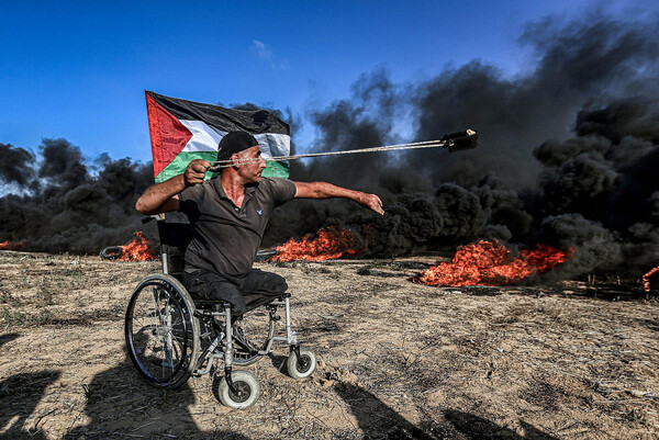 이스라엘 방위군에 휠체어에 앉아서 돌멩이를 던지며 맞서는 팔레스타인 주민/ 출처 – 팔레스타인 저항에 연대하는 사진가 Mohammed Zaanoun가 운영하는 ‘Activestills’ 사이트에서