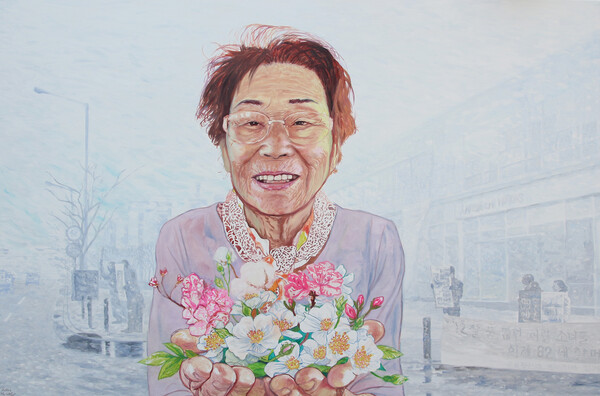 김화순 작 ‘선물’(130.3x193.9cm 캔버스에 유채 2023)“양금덕 할머니는 일제 강제동원 피해자다. 12살에 근로정신대로 끌려가 미쯔비시중공업에서 중노동을 했다. 양금덕 할머니는 오랫동안 일본의 사죄와 배상을 요구하며 싸우셨다. 그 과정에 대한민국 정부는 어떠한 도움도 되지 않았다. 심지어 2023년 윤 정부는 우리나라 기업에서 돈을 걷어 대신 보상금을 주겠다는 모욕적인 행태를 보이고 있다. “일본의 사과를 받는 것이 먼저다. 나는 그런 더러운 돈은 받지 않겠다.” 양금덕 할머니와 네 명의 원고들은 거부했고, 시민들은 함께 분노했다. 시민들은 역사정의시민모금으로 성금을 모아 네 분에게 전달했다. 모금액은 6억이 넘어갔고 현재도 진행 중이다.그림의 배경은 ‘근로정신대 할머니와 함께하는 시민모임’(현 일제강제동원시민모임)이 2009년 전범기업 미쯔비시자동차 광주전시장 앞에서 일본의 사죄와 배상을 요구하며 200일이 넘게 1인 시위를 하던 모습이다. 결국 광주전시장은 문을 닫았고, 긴 재판도 2018년 대법원 판결로 최종 승소했다.지난 8월 역사정의 시민모금 전달식에서 93세 양금덕 할머니는 환하게 웃으셨다. 서로에게 선물인 시민들과 할머니를 그림으로 남긴다.”