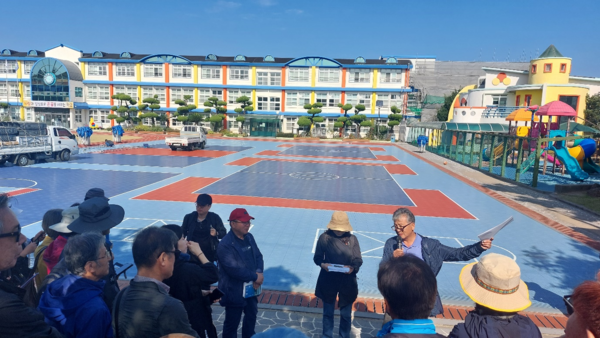 조천초등학교 앞에서 이 학교 졸업생인 김경훈 시인(맨 오른쪽부터), 허영선 제주4.3연구소장, 오승국 제주4.3평화투어기획위원장이 설명을 하고 있다. 토벌대는 주민들에게 이 학교로 모이라고 해놓고 집단학살을 저질렀다. © 이봉수