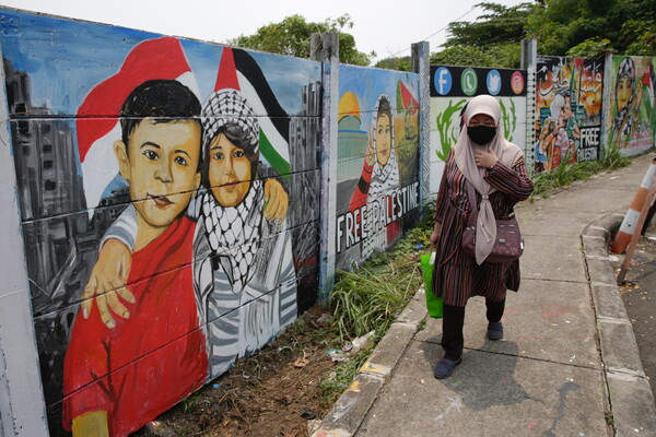 인도네시아 데폭에서 한 주민이 팔레스타인 지지의 뜻을 담은 벽화들 옆을 지나고 있다. 한 벽화에는 "자유로운 팔레스타인"이란 글귀가 씌어 있다. 2023 11. 08 [EPA=연합뉴스]
