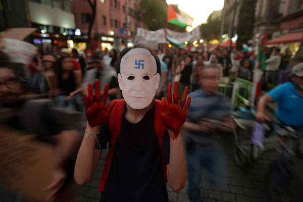 5일(현지시간) 멕시코시티에서 열린 팔레스타인 지지 시위에서 참가자가 이마에 나치 문양이 그려진 벤야민 네타냐후 이스라엘 총리의 가면을 쓰고 붉은 물감을 흠뻑 바른 양 손을 치켜든 채 행진하고 있다. 이스라엘은 자신들을 먼저 공격한 팔레스타인 무장정파 하마스를 궤멸시키겠다며 가자지구에 대한 공격을 멈추지 않고 있다. 2023.11.6. 로이터 연합뉴스