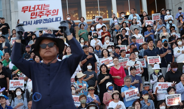 지난 9월8일 국회 본청 앞에서 열린 '윤석열 정권 폭정 저지·민주주의 회복 촛불 문화제'에서 한 시민이 '무너지는 민주주의 다시 세우겠습니다'라고 쓰인 종이피켓을 들고 시위를 벌이고 있다. 연합뉴스