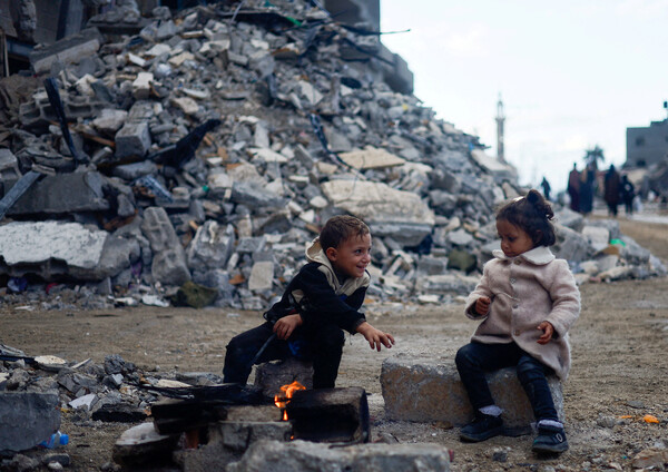 팔레스타인 어린이들이 27일 가자 남부 칸 유니스에서 이스라엘의 폭격으로 파괴된 건물더미 옆에서 불을 쬐고 있다. 2023 11. 27 [로이터=연합뉴스]