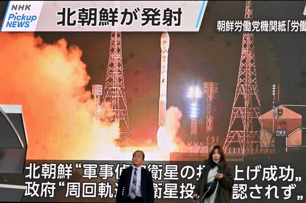 북한 군사정찰위성 1호기 '만리경-1호'의 발사 장면이 22일 일본 도쿄 아키하바라에서 방송되고 있는 가운데 시민들이 화면 앞을 지나가고 있다. 북한은 이날 만리경-1호를 궤도에 정확히 진입시켰다며 빠른 기간 내에 여러 개의 정찰위성을 발사할 계획이라고 밝혔다. 2023.11.22. AFP 연합뉴스