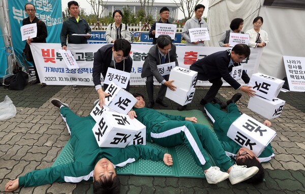 중소상인ㆍ금융소비자단체 회원들이 19일 오전 서울 여의도 국회 정문 앞에서 '가계부채 문제 해결 촉구' 기자회견을 마친 뒤 채무자들의 빚 탕감을 위해 정치권, 정부, 은행이 나서야 한다는 내용의 퍼포먼스를 하고 있다. 2023.10.19. 연합뉴스