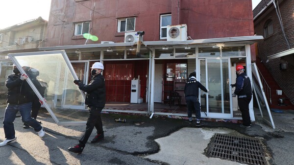 경기 파주시가 22일 업주와 종사자들의 반발에도 성매매 업소 집결지인 파주읍 연풍리 이른바 '용주골'의 법규 위반 건축물에 대한 강제 철거에 나선 가운데, 용역 업체 직원들이 통유리를 철거하고 있다. 2023.11.22. 연합뉴스