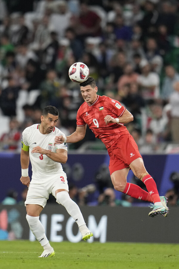 팔레스타인팀의 미드필더 타메르 세얌(오른쪽)이 14일 카타르 알라이얀의 에듀케이션 시티 스타디움에서 벌어진 이란과의 아시안컵 C조 경기 도중 점프해 볼을 따내고 있다. 세얌은 이날 전반 종료직전 헤더로 만회골을 뽑아 냈다.  2024. 01 14  [AP=연합뉴스]