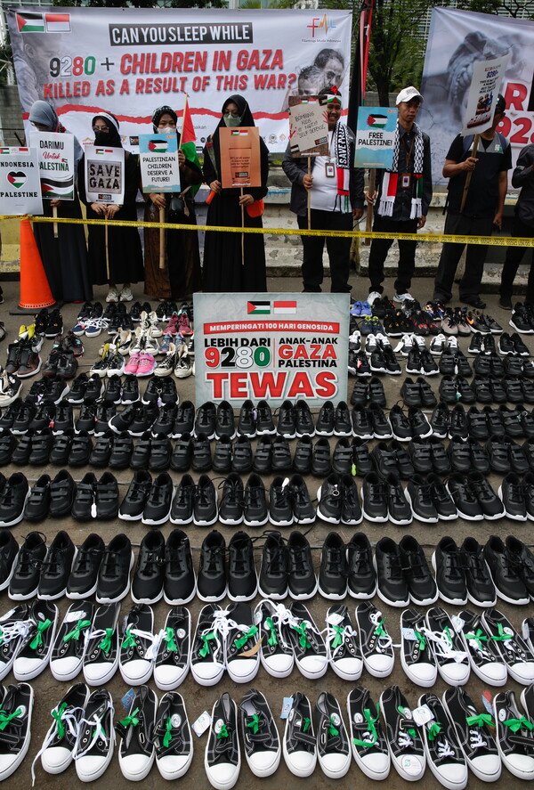 이스라엘과 팔레스타인 무장정파 하마스 간 전쟁 100일째인 14일(현지시간) 인도네시아 수도 자카르타의 미국대사관 앞에서 팔레스타인을 지지하는 무슬림들이 가자지구에서 숨진 어린이가 9280명이 넘는다며, 신발 수천 켤레를 진열해 놓고 반이스라엘 구호를 외치고 있다. 이 전쟁으로 필레스타인인 2만 3000여 명, 이스라엘인 약 1300명이 목숨을 잃은 것으로 알려졌다. 2024.01.15. EPA 연합뉴스