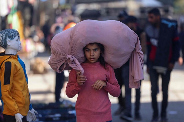 한 팔레스타이 소녀가 11일 가자 남부 라파의 북적이는 길거리에서 큰 보따리를 머리에 이고 걷고 있다. 2024. 02. 11 [AFP=연합뉴스] 