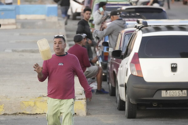 쿠바 아바나 시내의 한 도로에서 2일 자동차들이 휘발유를 사기 위해 줄지어 기다리고 있다. 한 남자가 자신의 연료통을 공중에 던지고 있다. 미겔 디아스카넬 쿠바 국가평의회 의장은 이날 에너지난 와중에 경제장관을 경질했다. 2024.2.2. AP 연합뉴스 