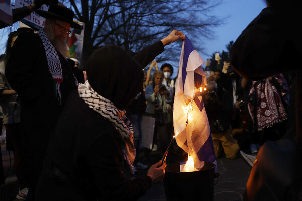 애런 부시넬이 이스라엘의 가자지구 학살에 항의해 분신한 미국 워싱턴의 이스라엘 대사관 앞에서 26일 시위자들이 이스라엘 국기를 불태우고 있다. 2024.2.26. AFP 연합뉴스 