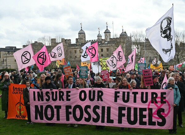 지난 28일 런던 트리니티 스퀘어 가든에서 기후 변화 대응단체 '멸종 저항'(XR)이 주최한 시위 행진을 앞두고 참가자들이 화석연료 사용 반대 구호를 적은 플래카드와 깃발들을 흔들고 있다. 2024.2.28. AFP 연합뉴스