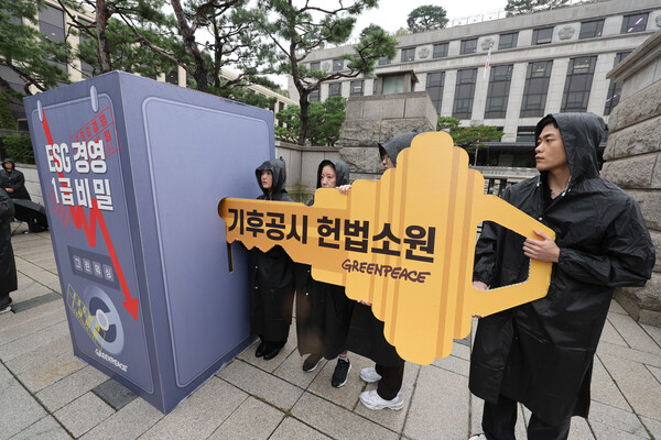 환경단체 그린피스 관계자들이 20일 오전 서울 종로구 헌법재판소 앞에서 기후공시 제도 도입 촉구 헌법소원 제출에 앞서 관련 퍼포먼스를 하고 있다. 2023.9.20. 연합뉴스