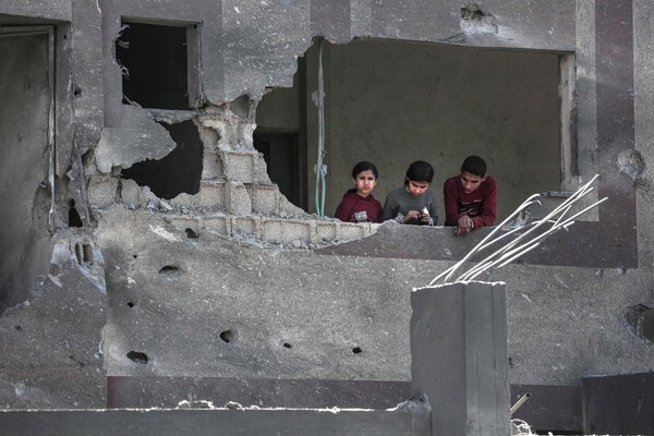 가자지구 중부의 누세이라트 난민 캠프에 대한 이스라엘의 심야 폭격으로 파괴된 건물 창문을 통해 팔레스타인 아이들이 바깥을 바라보고 있다. 2024. 03. 20 [AFP=연합뉴스]