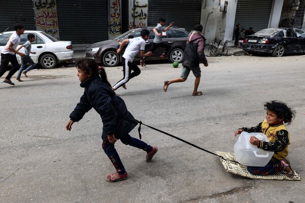 가자 최남단 국경도시 라파에서 팔레스타인 아이들이 한편에선 공놀이, 다른 한편에선 썰매 놀이를 하고 있다. 이스라엘 극우 정권은 라파에 대한 지상군 공격 계획을 밝혔다. 2024. 03. 22. [AFP=연합뉴스]