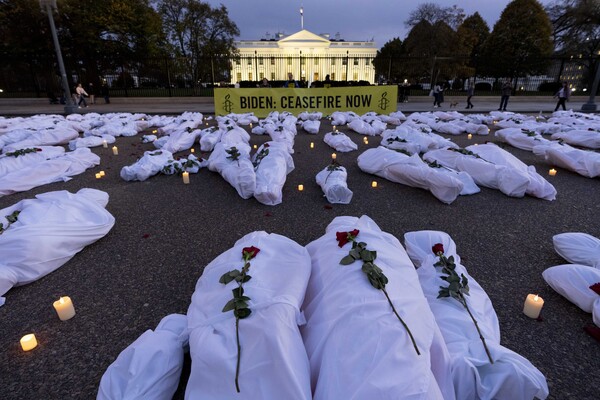 미국 워싱턴D.C. 백악관 앞에 팔레스타인인 사망자를 뜻하는 하얀 주검들 정렬돼 있고, 그 위에는 꽃들이, 곁에는 촛불들이 놓여 있다. 이번  퍼포먼스는 앰네스티 인터내셔널 미국 지부가 주도했다. 펼침막에는 "바이든 당장 휴전하라"는 문구가 씌어 있다. 2023. 11. 15  [AP=연합뉴스]