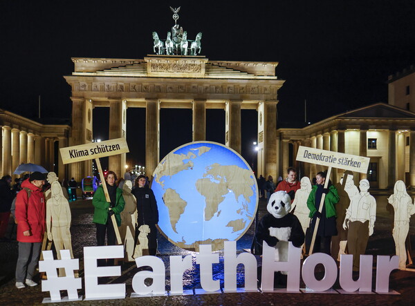 지난 23일 '지구 시간' 조명 끄기 행사 직전의 독일 베를린 브란덴부르크 문 앞의 모습. 지구 시간은 기후 변화에 맞서 싸우는 인식을 높이기 위해, 이날 오후 8시 30분(세계 각국 현지시각)부터 60분 동안 조명을 꺼 탄소 배출을 줄여야 한다는 전 지구적 요청을 부각시키는 행사다. 피켓의 글귀는 '기후 보호'(왼쪽)와 '민주주의 강화' 2024.3.23. EPA 연합뉴스