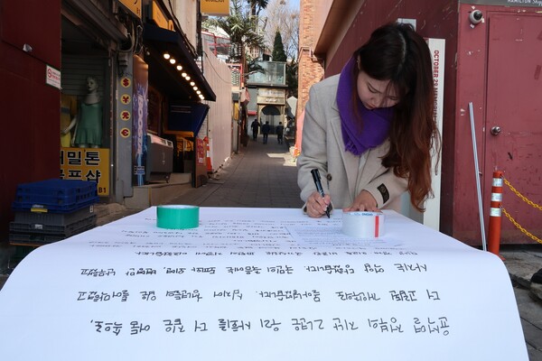 2030 유권자네트워크의 청년세대 투표 참여 호소 릴레이 대자보에 참여한 유정은씨가 21일 오후 서울 용산구 이태원 참사 추모의 벽 앞에서 대자보를 쓰고 있다. 이태원 참사 희생자 유연주씨의 언니인 정은씨는 "지겨운 절망을 넘어, 내일을 위해 투표합시다"란 제목의 대자보를 썼다. 2024.3.21 연합뉴스