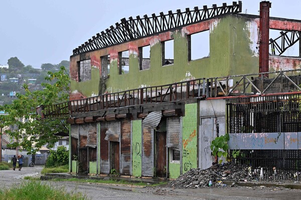 총선 전야인 16일 솔로몬제도 수도 호니아라의 차이나타운에서 주민들이 폐건물을 지나가고 있다. 차이나타운 상인들은 친중국 노선의 머내시 소가바레 총리가 또 당선될 경우 자신들을 향해 벌어질지 모를 대규모 폭력사태를 우려하고 있다. 2024. 04. 16 AFP=연합뉴스