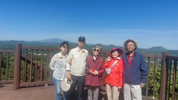 최만자-여무현 일가족이 키아오라 뒤 오름인 대수산봉 전망대에 올라 설명을 듣고 한라산을 배경으로 사진을 찍었다. © 이봉수
