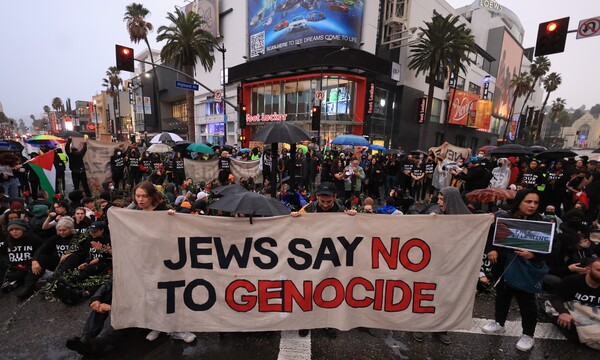 미국 캘리포니아주 로스앤젤레스에서 유대인 운동가들이 할리우드와 하이랜드 교차로믈 막고 팔레스타인 가자지구에서 휴전을 촉구하고 있다. 펼침막에는 "유대인들은 제노사이드에 반대한다고 말한다"란 글귀가 씌어있다. 2023. 11. 15 [EPA=연합뉴스]